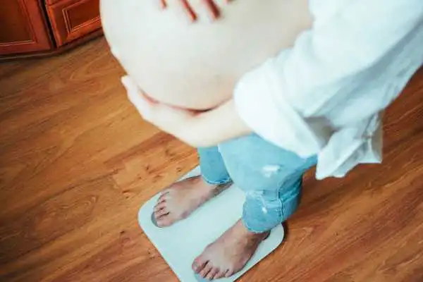 Image of woman weighing herself and experiencing weight gain through pregnancy Marlow